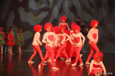 [Bilde av dansere på scenen som er kledd som hjertere fra Alice in Wonderland. De har røde parykker og røde bukser. På magen har de stort rødt hjerte.] 