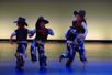 Bilde av fire elever fra barnedans som danser krokarm rundt og rundt to og to. De er kledd i cowboyklær.