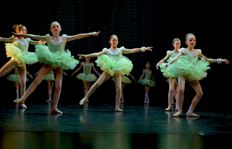 Bildet viser fem ballettdansere på scenen. De har på seg grønne tutu kjoler. 
