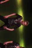 Bildet viser jente på scenen i glittertopp. Hun danser jazzdans og står i bred posisjon med beina og har hendene på hoftene. 