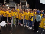 Bilde viser juniorkoret synge konsert i gule t-shirts.