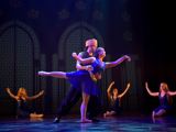 [Bildet viser en gutt og ei jente som danser sammen på scenen. Jenta holdes i en balllettposisjon av gutten. Han støtter henne. Beinet til jenta er 90 grader rett ut bak i en arabesque posisjon. Hun har blå glitterkjole på seg, og gutten har svarte klær og gullhatten. Han ser ut som en prins.] 